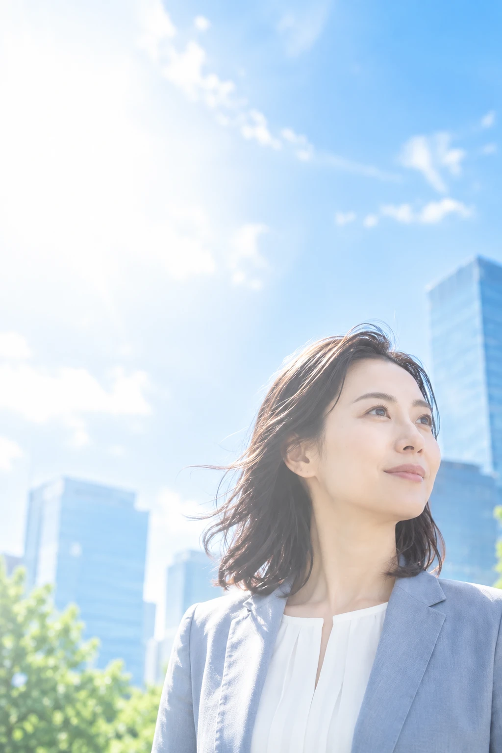 明るい都市と空を背景に、未来を見つめる女性の横顔